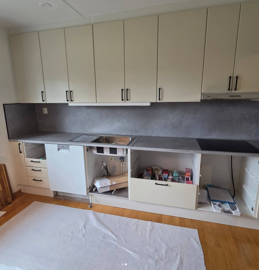 Kök efter renovering med grå bänkskiva och matchande stänkskydd.